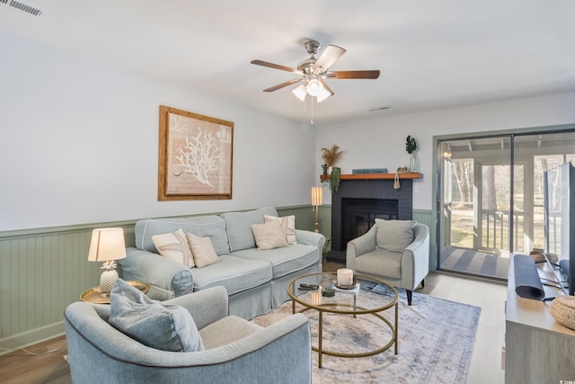 living room with visible vents, wood finished floors, and wainscoting