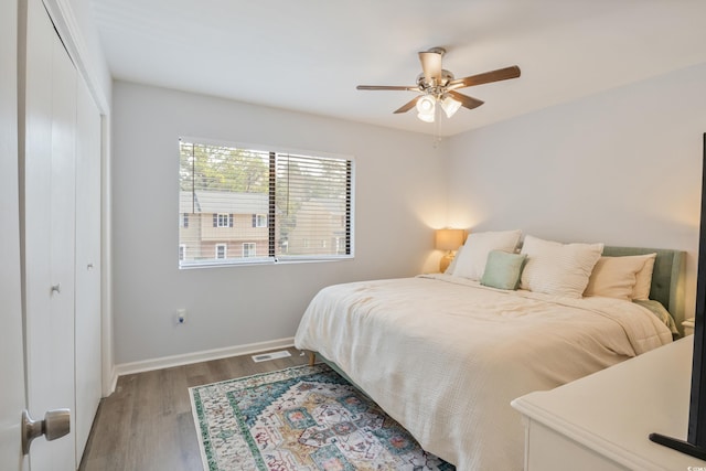 bedroom featuring baseboards, visible vents, a ceiling fan, wood finished floors, and a closet