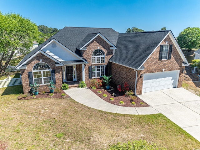 craftsman-style home with brick siding, driveway, a front yard, and fence