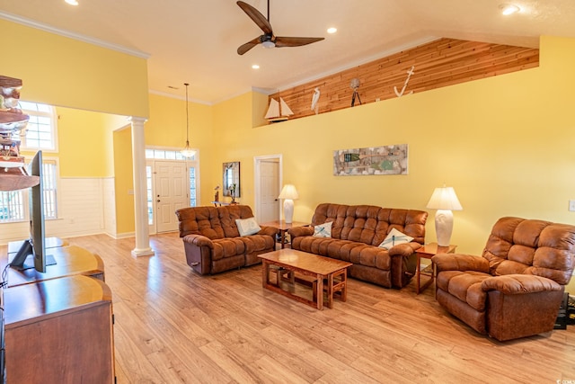 living area with high vaulted ceiling, ceiling fan, light wood finished floors, ornamental molding, and ornate columns