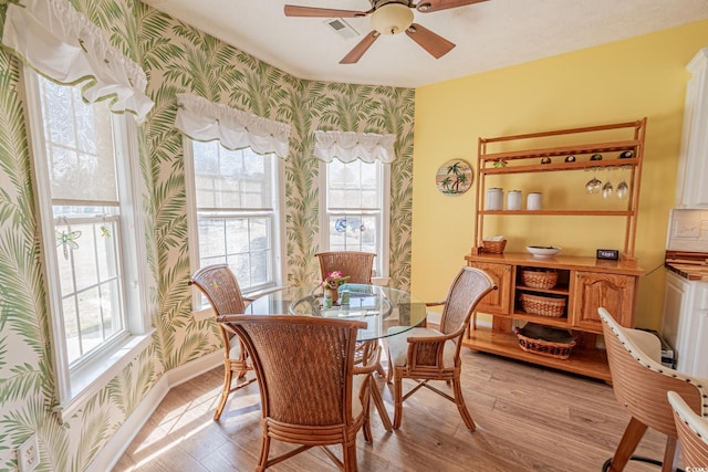 dining space featuring light wood-type flooring, wallpapered walls, visible vents, and a wealth of natural light