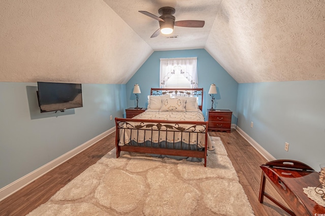 bedroom with lofted ceiling, a ceiling fan, wood finished floors, and a textured ceiling
