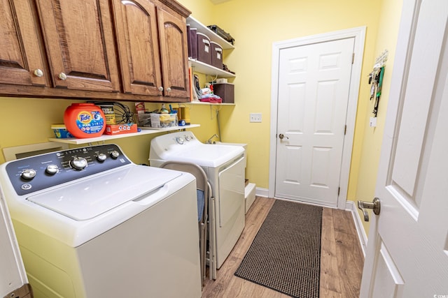 laundry area featuring washing machine and clothes dryer, cabinet space, light wood finished floors, and baseboards