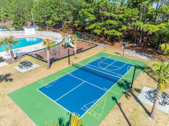 view of sport court with fence, playground community, and a community pool