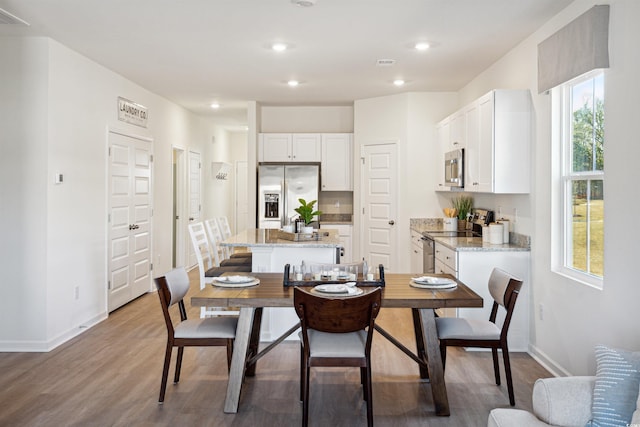 dining room featuring light wood-type flooring, visible vents, baseboards, and recessed lighting