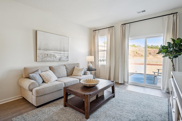 living room featuring baseboards, visible vents, and light wood finished floors