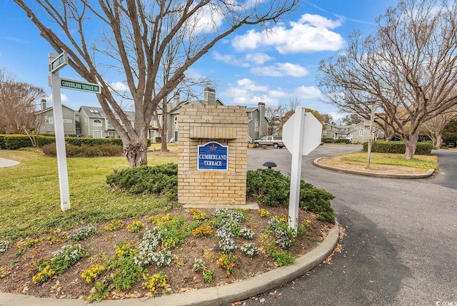 community / neighborhood sign featuring a yard and a residential view