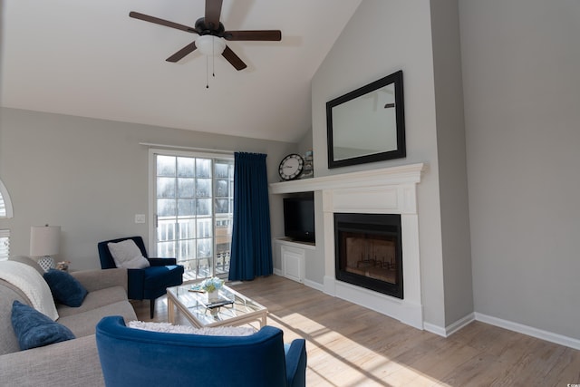 living area featuring wood finished floors, a fireplace, baseboards, a ceiling fan, and vaulted ceiling