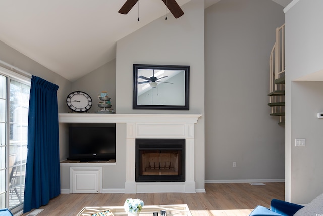 living area with ceiling fan, vaulted ceiling, wood finished floors, and a fireplace