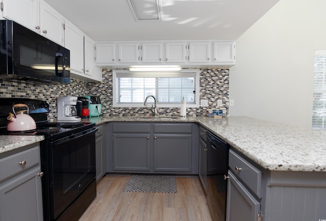 kitchen featuring light wood-style flooring, gray cabinets, a sink, and black appliances