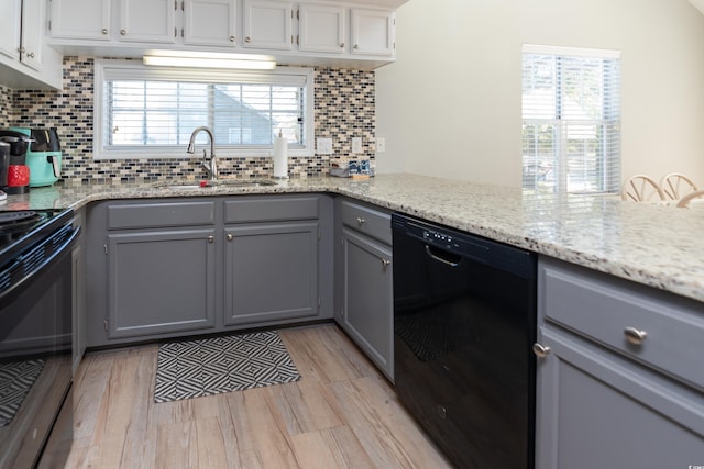 kitchen with a sink, decorative backsplash, gray cabinetry, and black appliances