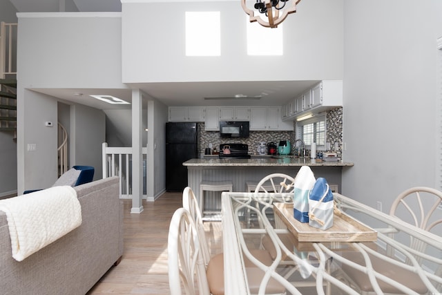 dining area with baseboards, light wood finished floors, a high ceiling, and a notable chandelier
