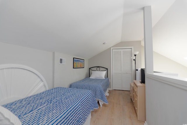 bedroom featuring visible vents, light wood finished floors, and lofted ceiling