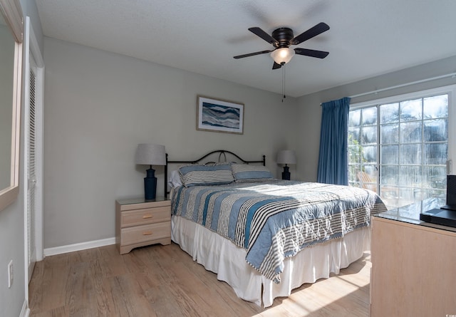 bedroom with a ceiling fan, baseboards, and light wood-type flooring