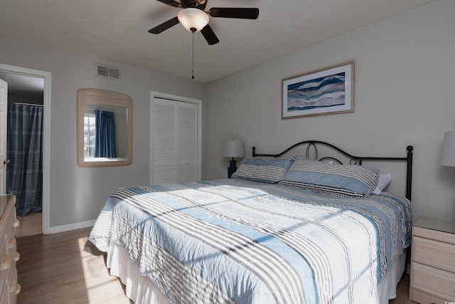 bedroom with ceiling fan, baseboards, wood finished floors, visible vents, and a closet