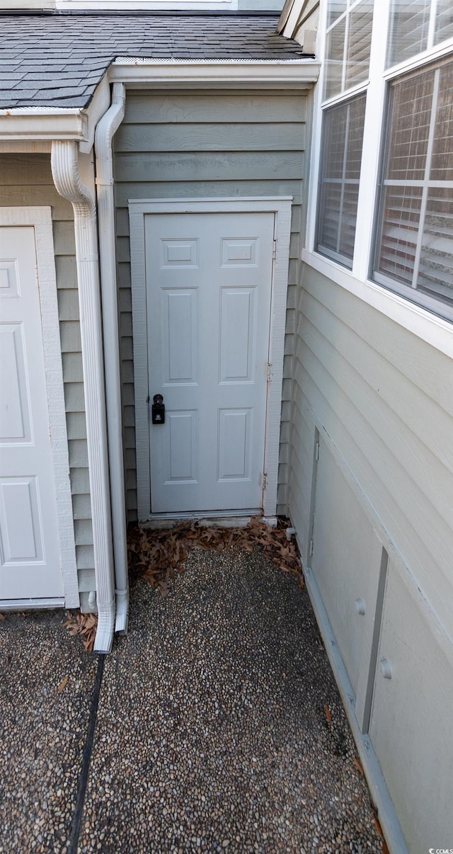 view of exterior entry with a shingled roof