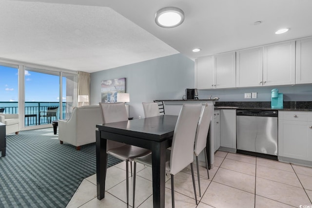 kitchen with a water view, stainless steel dishwasher, expansive windows, open floor plan, and white cabinets