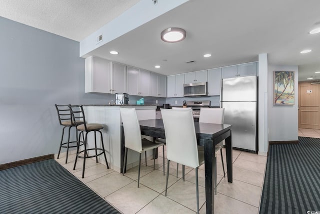 kitchen with dark countertops, visible vents, appliances with stainless steel finishes, white cabinetry, and a kitchen breakfast bar