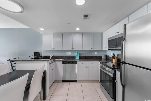 kitchen featuring stainless steel appliances, visible vents, white cabinetry, and a peninsula