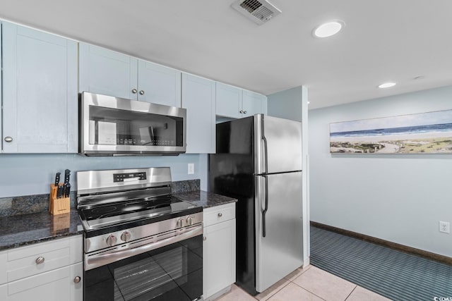 kitchen with light tile patterned floors, stainless steel appliances, visible vents, white cabinets, and dark stone countertops