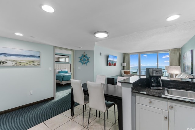 interior space featuring light tile patterned flooring, light colored carpet, white cabinetry, baseboards, and open floor plan