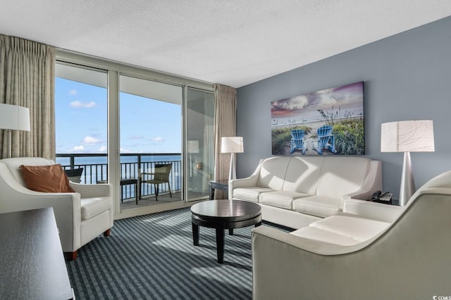 living room featuring a water view, floor to ceiling windows, carpet floors, and a textured ceiling