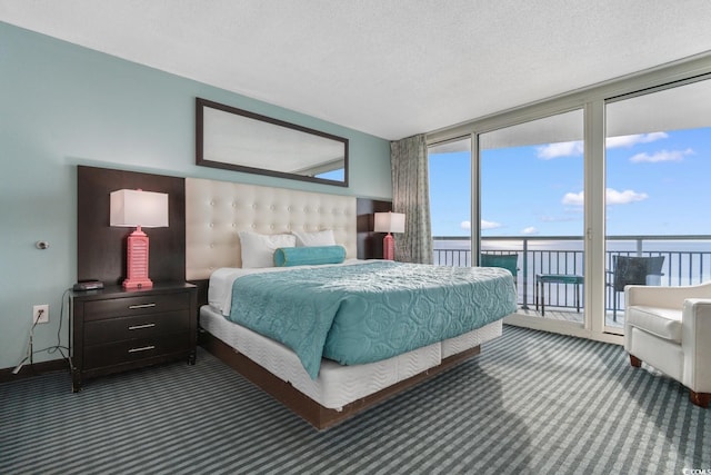 carpeted bedroom with a water view, access to outside, floor to ceiling windows, and a textured ceiling