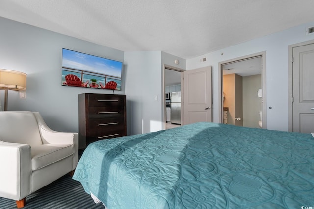 bedroom with freestanding refrigerator, visible vents, a textured ceiling, and carpet