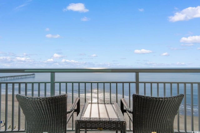 balcony featuring a view of the beach and a water view