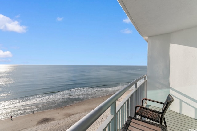 balcony with a water view and a view of the beach