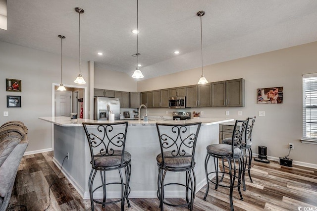 kitchen featuring a breakfast bar area, appliances with stainless steel finishes, dark wood finished floors, and light countertops