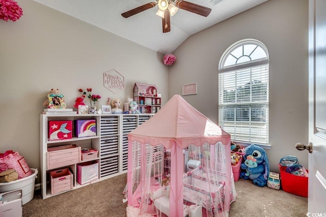 recreation room featuring a ceiling fan, vaulted ceiling, carpet flooring, and a healthy amount of sunlight