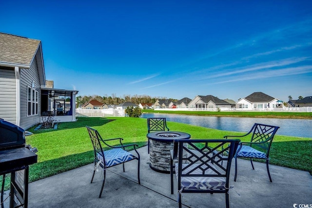 view of patio featuring fence, a fire pit, a water view, a residential view, and a grill