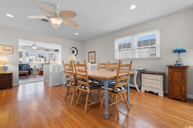 dining room with a healthy amount of sunlight, light wood finished floors, a textured ceiling, and recessed lighting