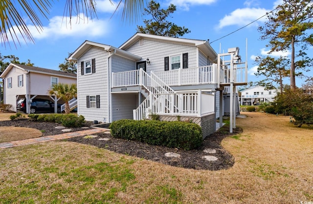 raised beach house featuring a deck, stairway, and a front yard