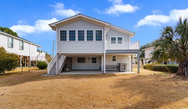 rear view of property featuring a lawn, a patio area, a carport, driveway, and stairs