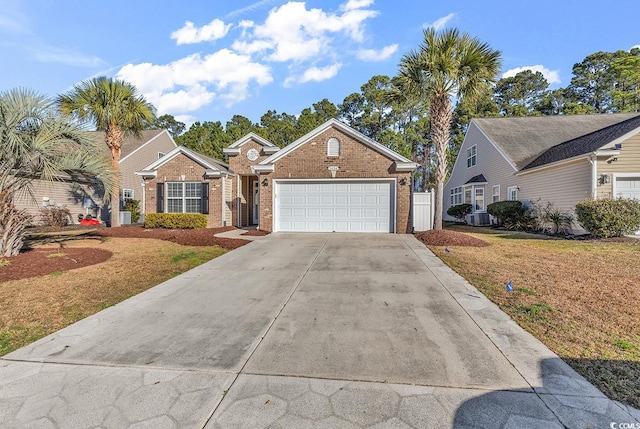 view of front of home featuring central AC unit, an attached garage, brick siding, driveway, and a front yard