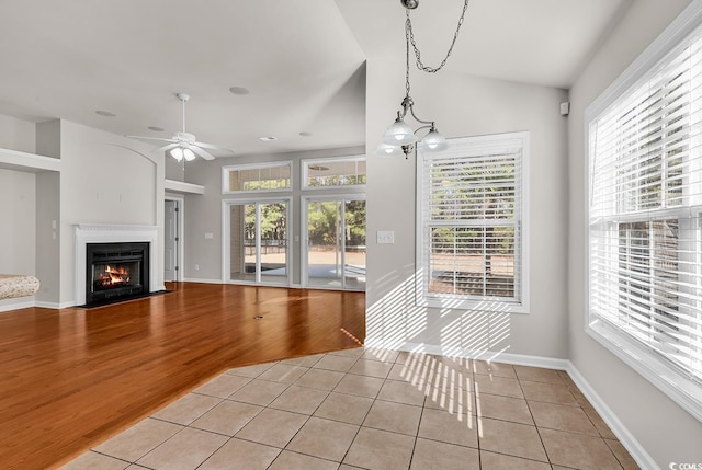 unfurnished living room featuring a fireplace with flush hearth, a healthy amount of sunlight, and light wood-style flooring