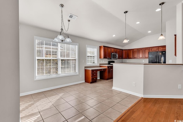 kitchen with visible vents, light countertops, black fridge, stainless steel microwave, and decorative light fixtures