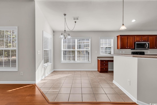 kitchen with hanging light fixtures, visible vents, stainless steel microwave, and baseboards