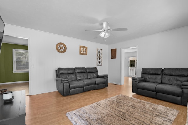 living area with baseboards, a ceiling fan, and wood finished floors