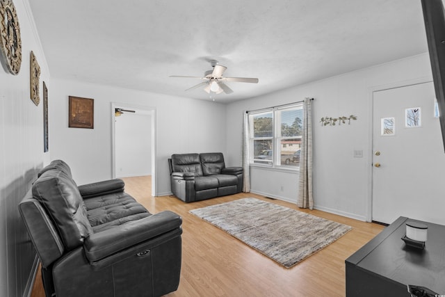 living area featuring light wood-style floors, ceiling fan, and baseboards