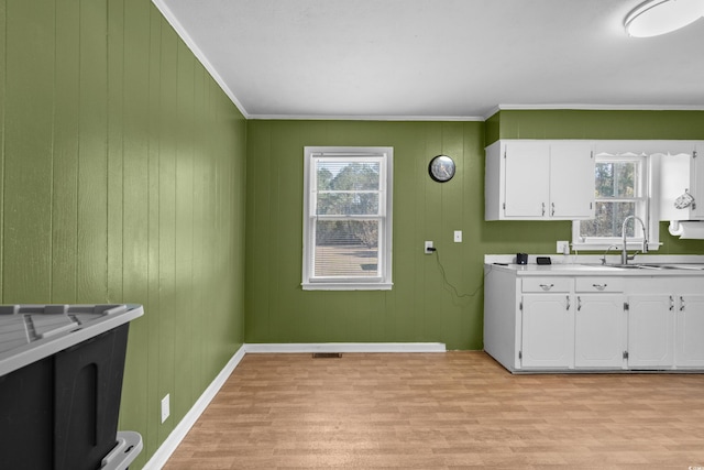 interior space featuring a healthy amount of sunlight, light wood-style floors, white cabinetry, and a sink