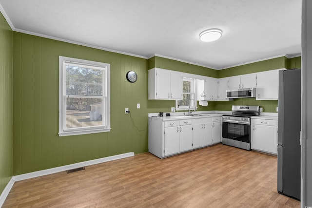 kitchen with white cabinetry, light wood-style floors, light countertops, ornamental molding, and appliances with stainless steel finishes