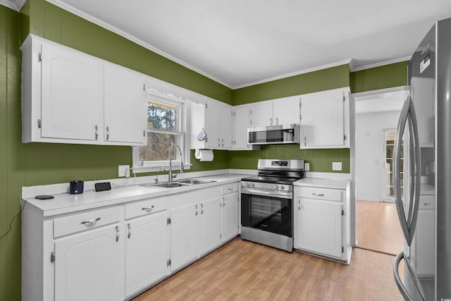 kitchen with stainless steel appliances, light wood-type flooring, white cabinets, and a sink