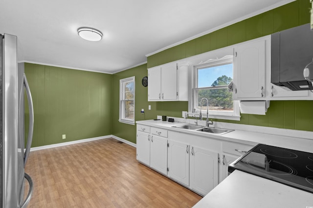 kitchen featuring light countertops, a sink, freestanding refrigerator, and white cabinets