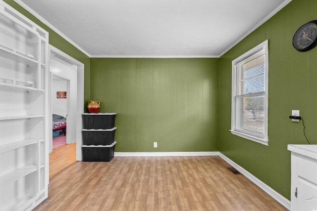 spare room with baseboards, ornamental molding, visible vents, and light wood-style floors