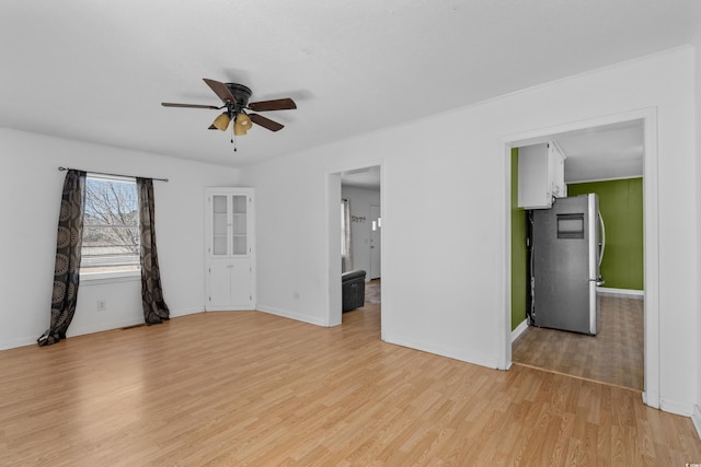 unfurnished room featuring light wood finished floors, a ceiling fan, and baseboards