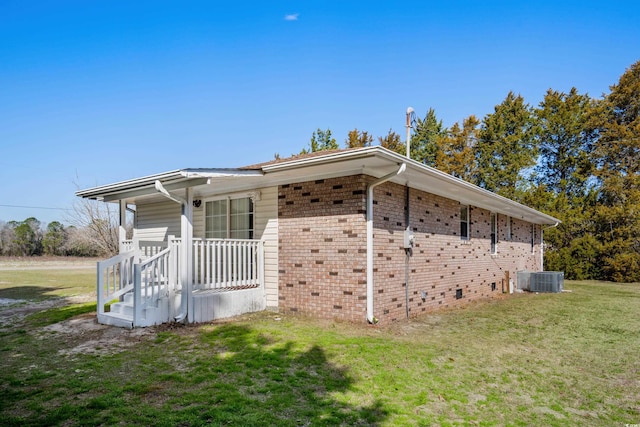 view of side of home featuring brick siding, a lawn, and cooling unit