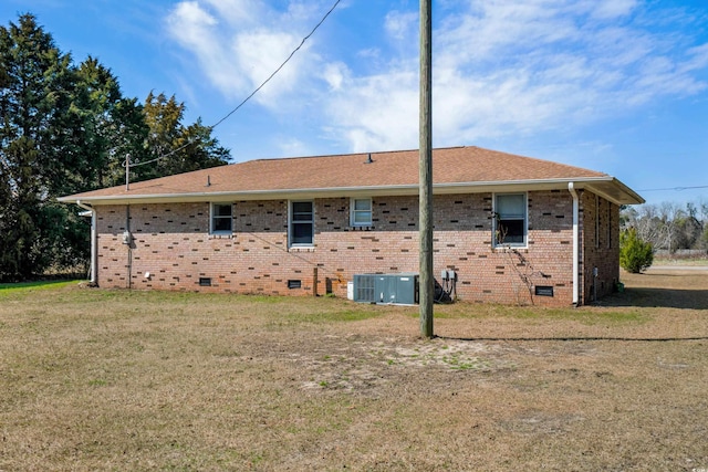 back of property with crawl space, brick siding, a yard, and roof with shingles